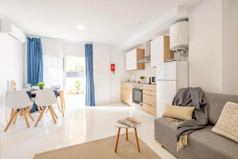 Espace de vie lumineux avec coin repas et canapé gris.