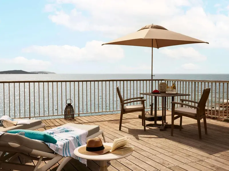 Terrasse en bois avec mobilier de jardin et vue sur la mer.