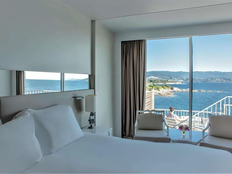 Chambre lumineuse avec vue sur la mer et un balcon.