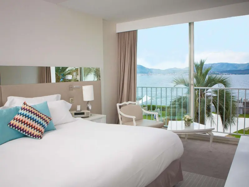Une chambre lumineuse avec un grand lit donnant sur la mer.
