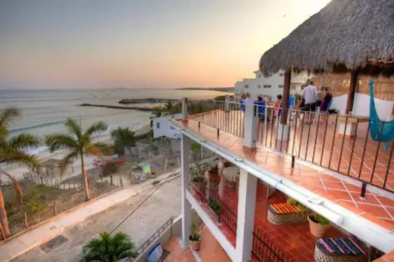 Terrasse ensoleillée avec vue sur la mer et quelques personnes assises à table.