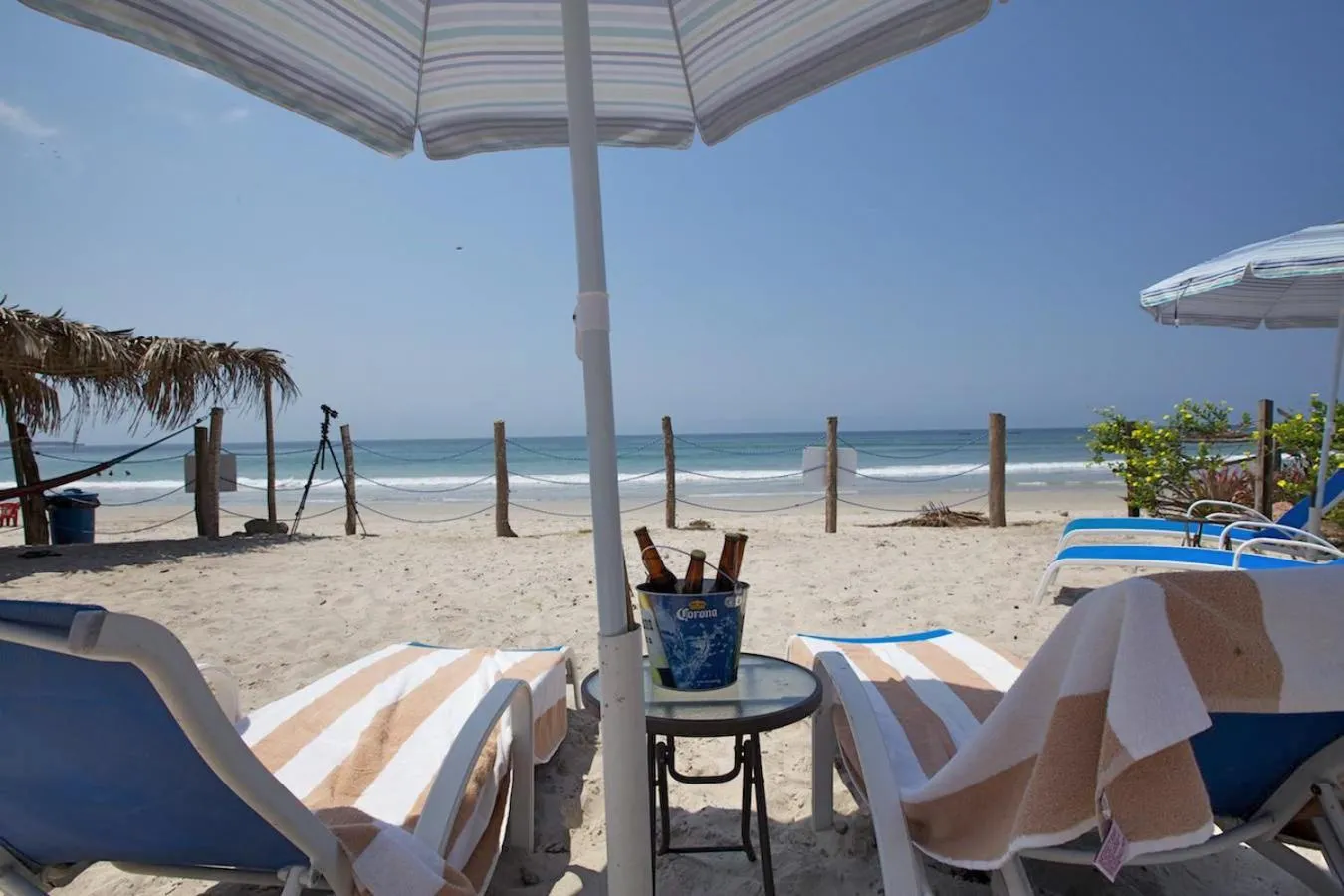 Transats et table basse sur une plage de sable fin avec vue sur la mer.
