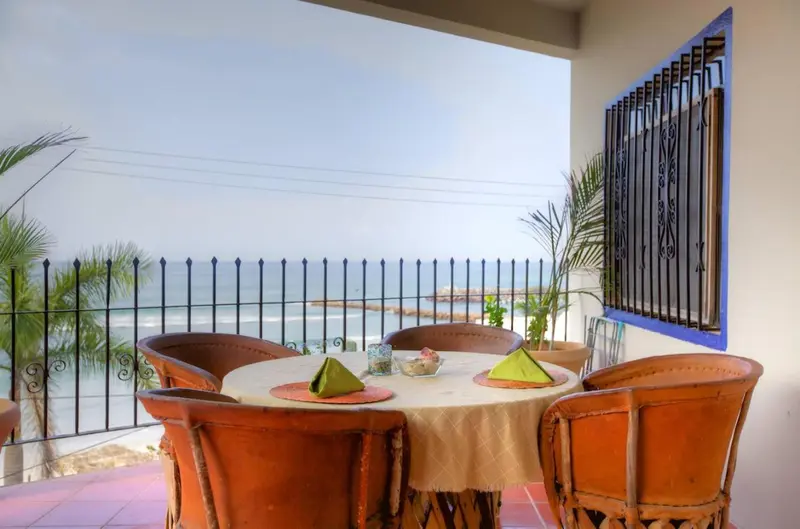 Une table à manger est mise en scène sur une terrasse avec vue sur la mer.