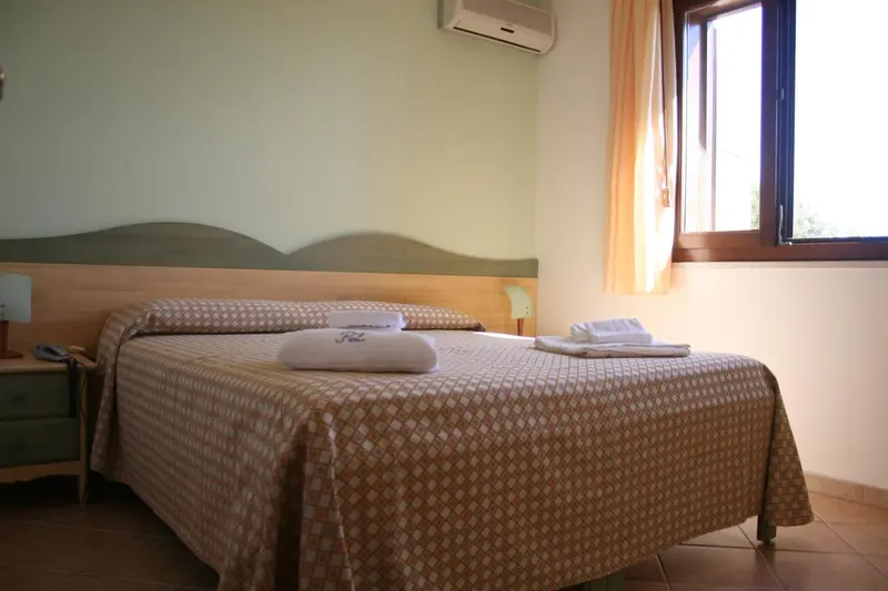 Une chambre lumineuse avec un lit double et une fenêtre.