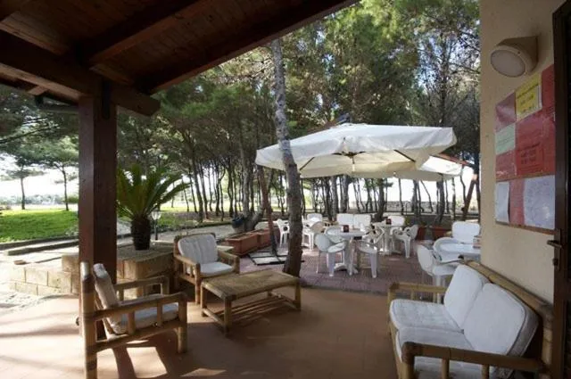 Terrasse ombragée avec mobilier blanc et végétation luxuriante.