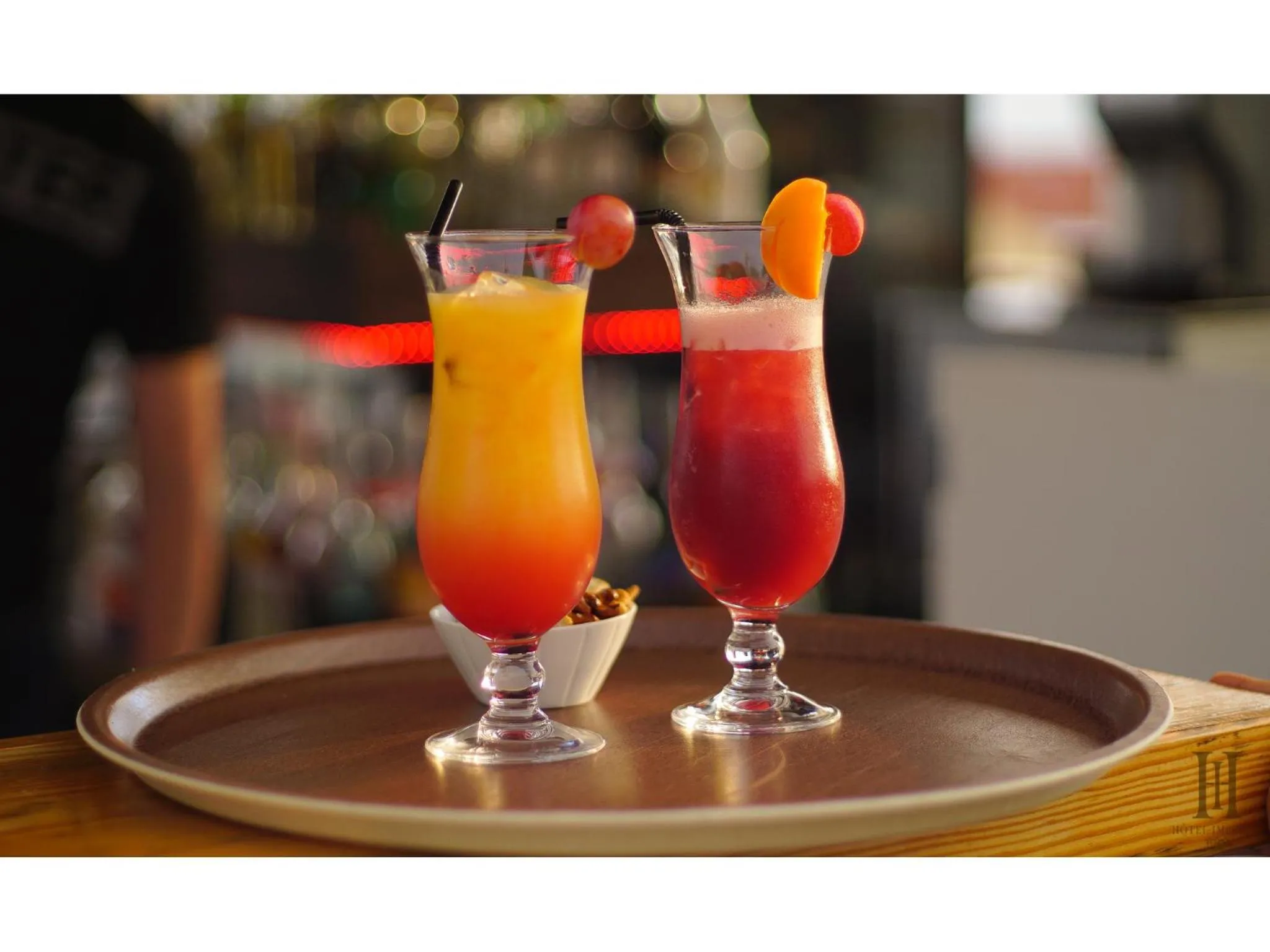 Deux cocktails colorés sont servis sur un plateau en bois.