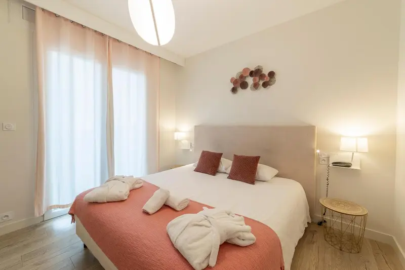 Une chambre lumineuse avec un grand lit recouvert d'une courtepointe et de coussins.