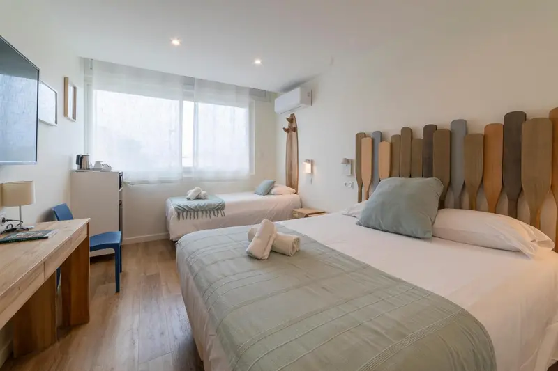 Chambre lumineuse avec deux lits simples et une décoration murale en bois.