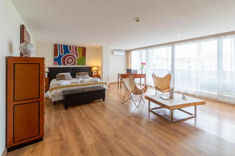 Une chambre lumineuse avec un grand lit et un coin salon.