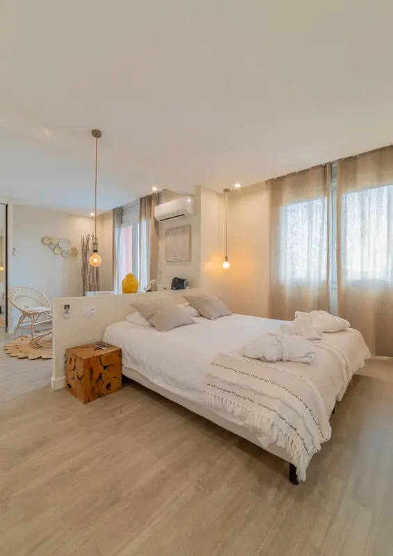 Une chambre lumineuse avec un grand lit recouvert de linge blanc.