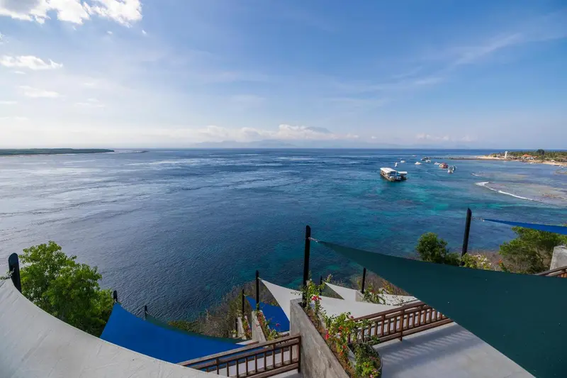 Vue panoramique sur la mer et la côte depuis une terrasse en hauteur.