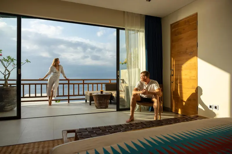 Une chambre lumineuse s'ouvre sur une terrasse avec vue sur la mer.