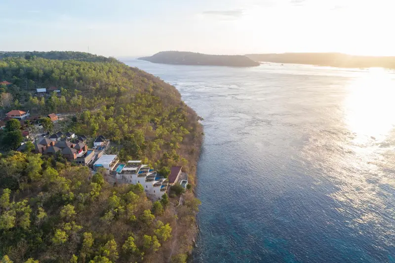 Vue aérienne d'un complexe hôtelier sur une côte rocheuse ensoleillée.