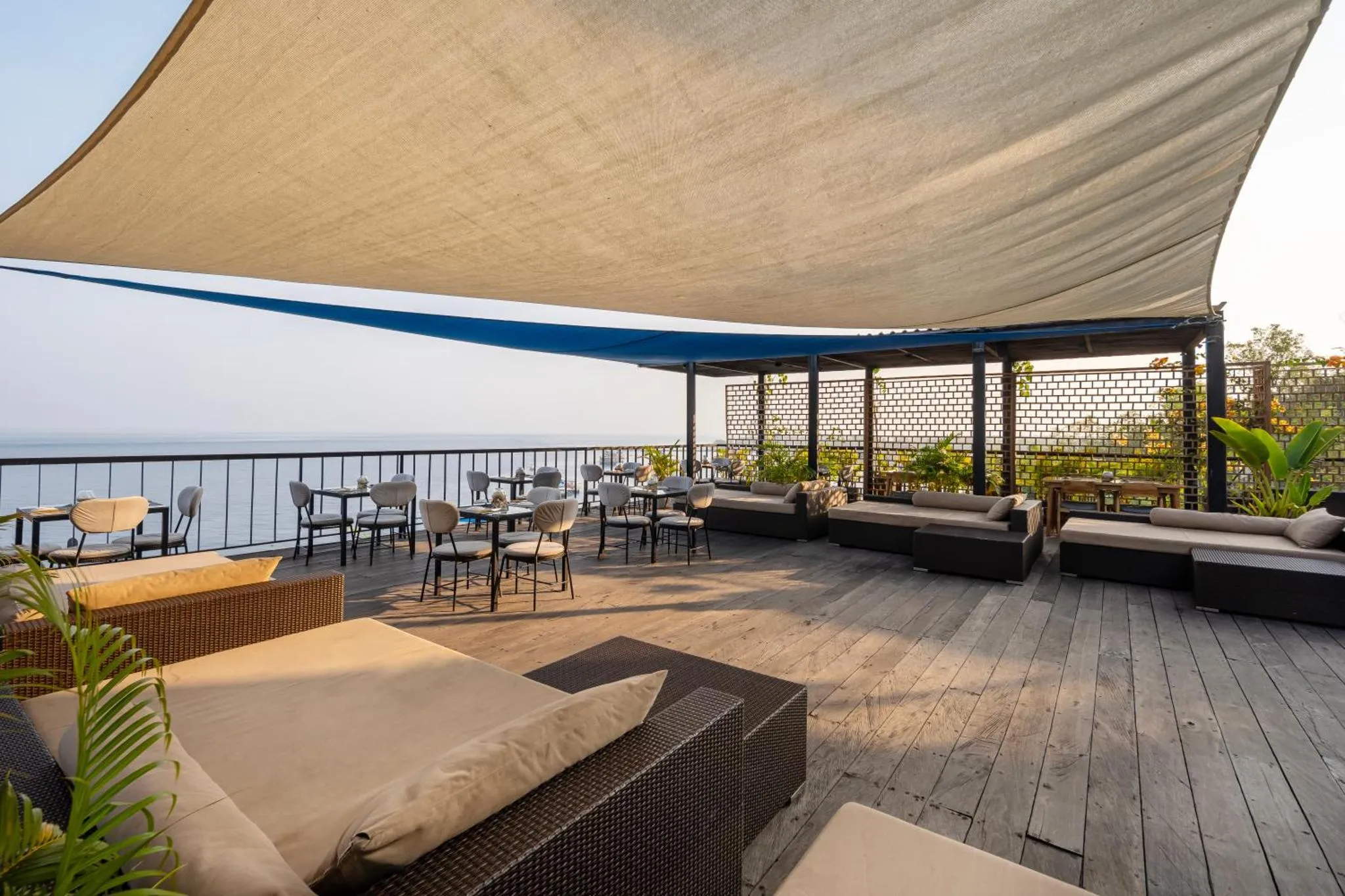 Terrasse ombragée avec mobilier de détente et vue sur la mer.