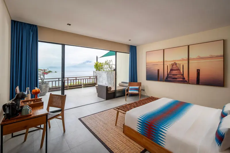 Une chambre lumineuse avec un lit et un accès à une terrasse offrant une vue sur la mer.