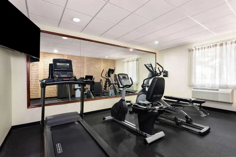 Une salle de sport lumineuse avec plusieurs appareils de fitness et des miroirs.
