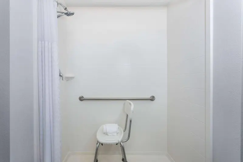 Douche accessible avec siège et barre d'appui.
