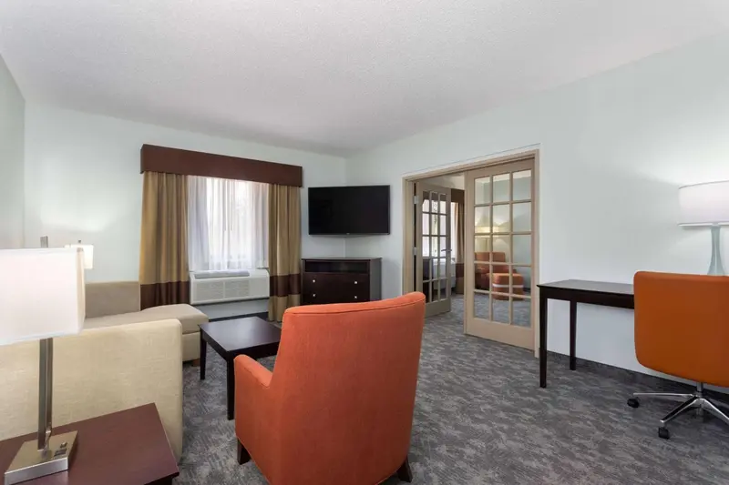 Espace de séjour lumineux avec canapé, fauteuil et bureau.