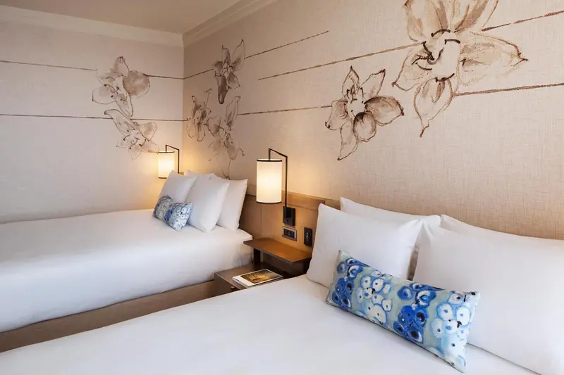 Deux lits simples dans une chambre décorée de motifs floraux.