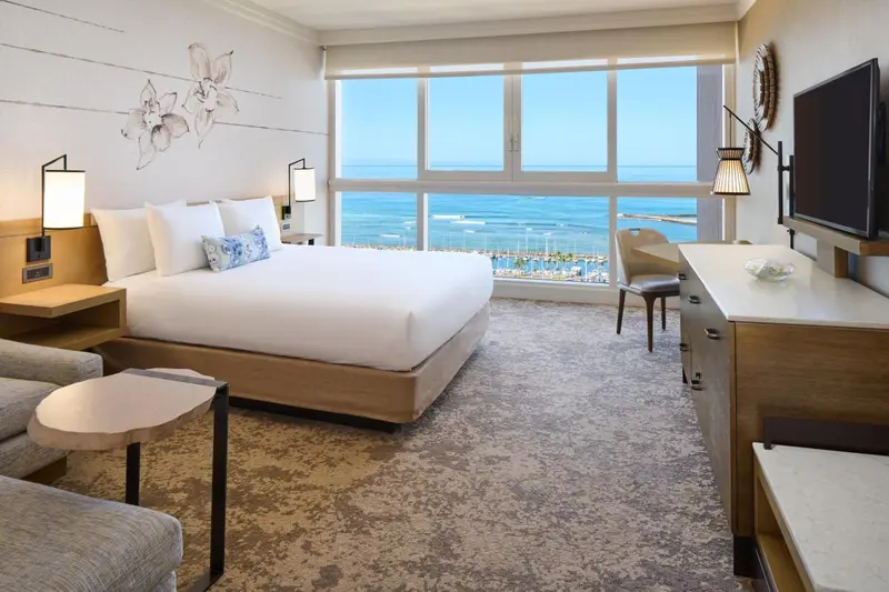Chambre lumineuse avec un grand lit donnant sur la mer.