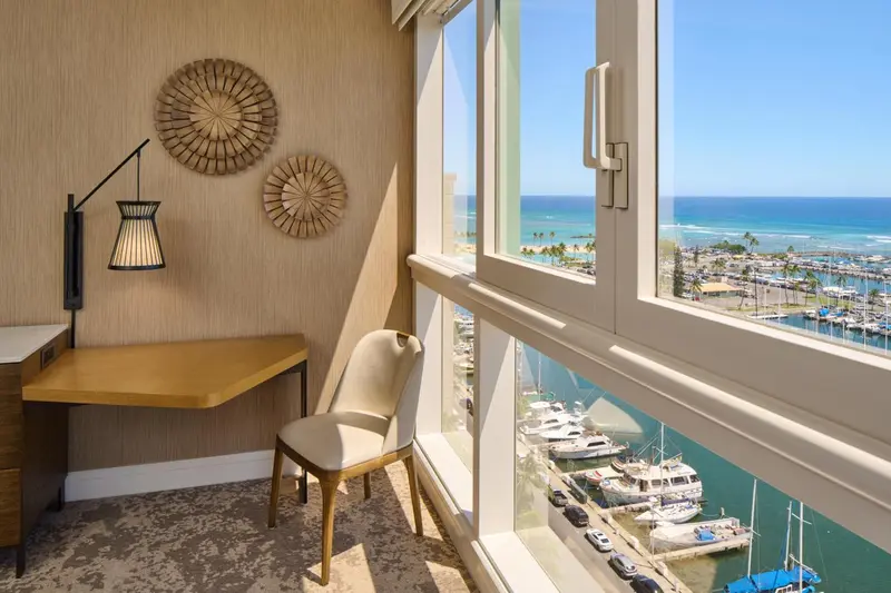 Une chambre lumineuse avec un bureau et une vue sur la mer.