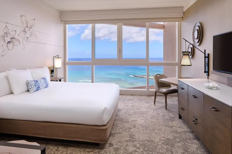 Chambre lumineuse avec un grand lit et vue sur la mer.