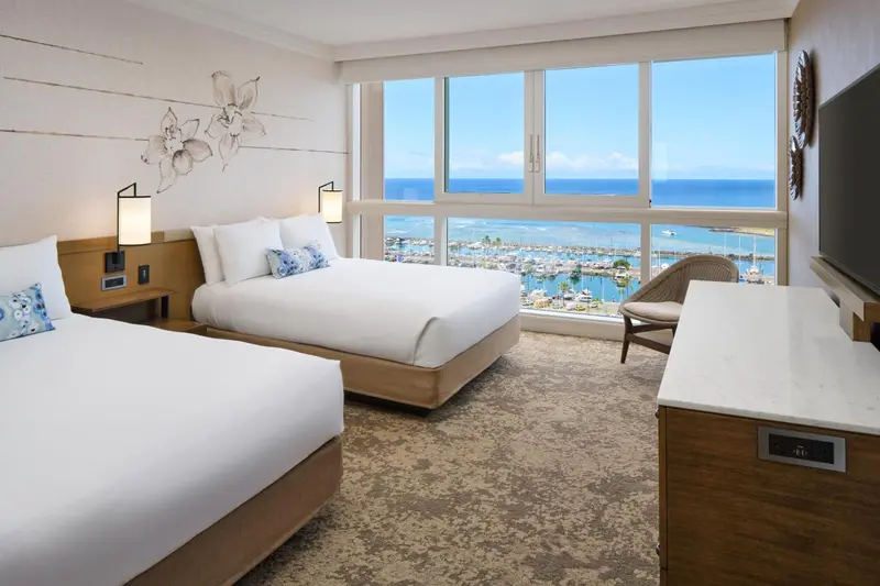 Chambre lumineuse avec deux lits et vue sur la mer.