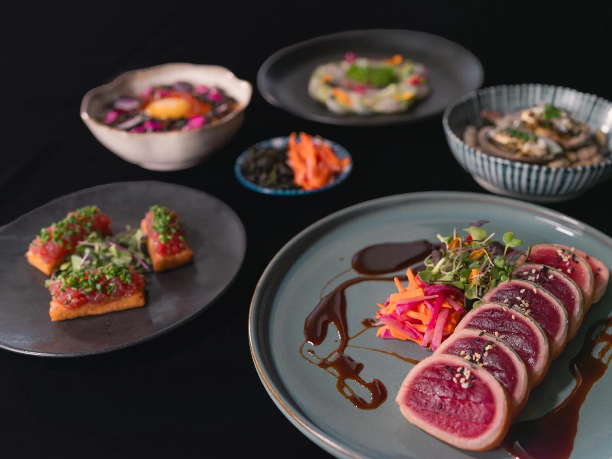 Assortiment de plats raffinés présentés sur des assiettes de différentes formes et couleurs.