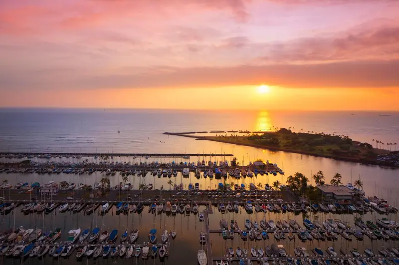 Coucher de soleil sur une marina avec de nombreux bateaux amarrés.