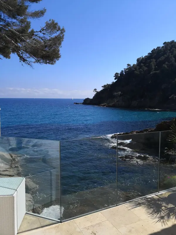 Vue sur une crique rocheuse et la mer depuis une terrasse ensoleillée.
