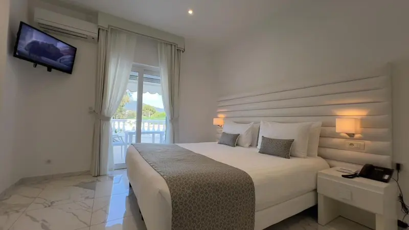 Chambre lumineuse avec un grand lit et un accès à un balcon.
