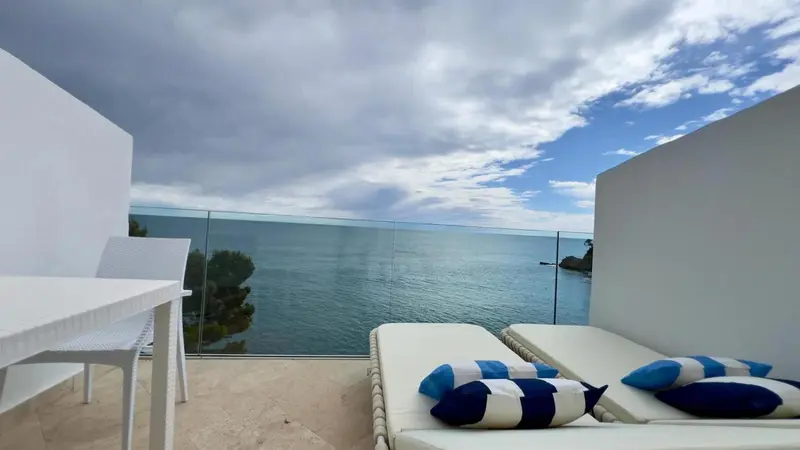 Terrasse avec mobilier blanc donnant sur la mer.