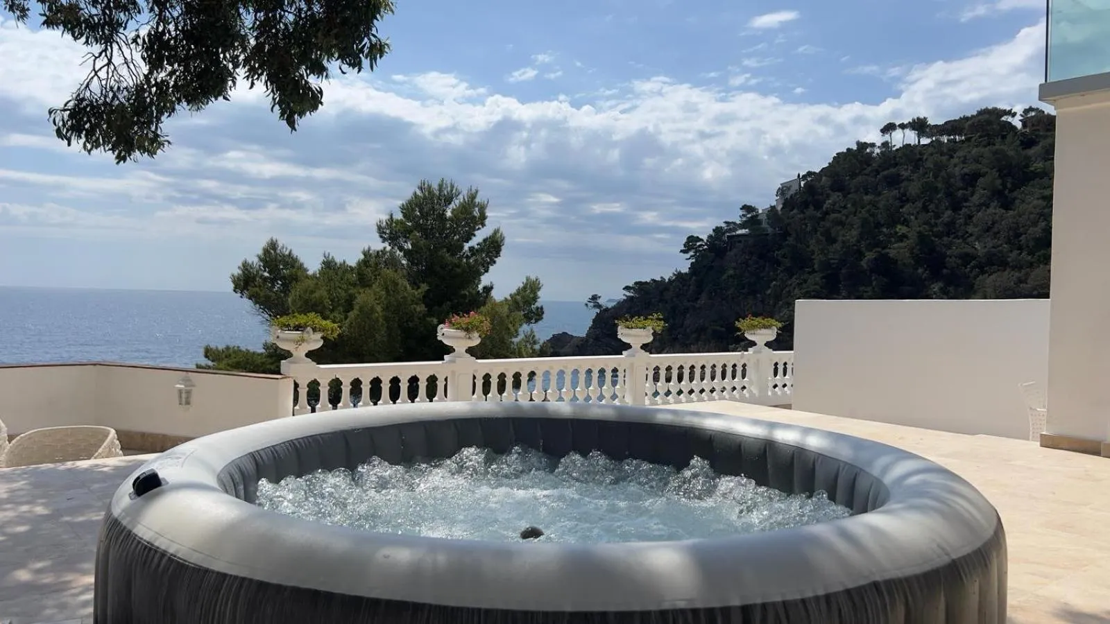 Un jacuzzi sur une terrasse avec vue sur la mer et la végétation.