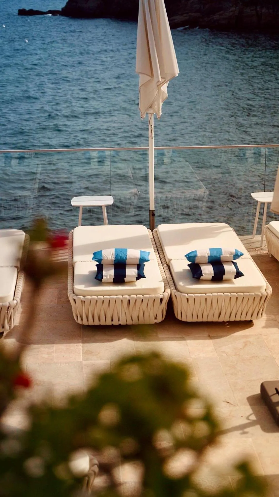 Transats blancs disposés sur une terrasse ensoleillée avec vue sur la mer.