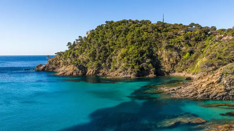 Côte rocheuse surplombant une crique aux eaux turquoise.
