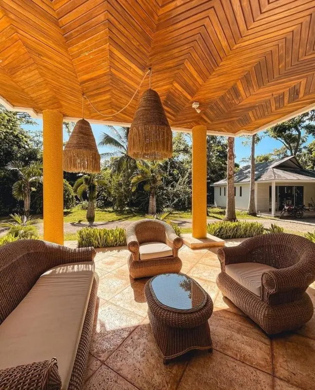 Espace de détente extérieur avec mobilier en rotin sous une structure en bois.