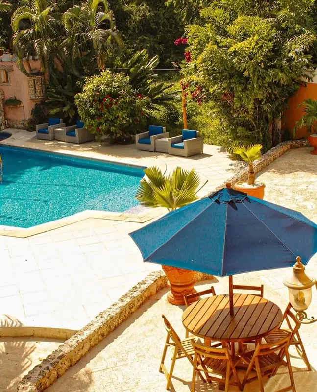 Terrasse avec transats et table basse près d'une piscine ensoleillée.