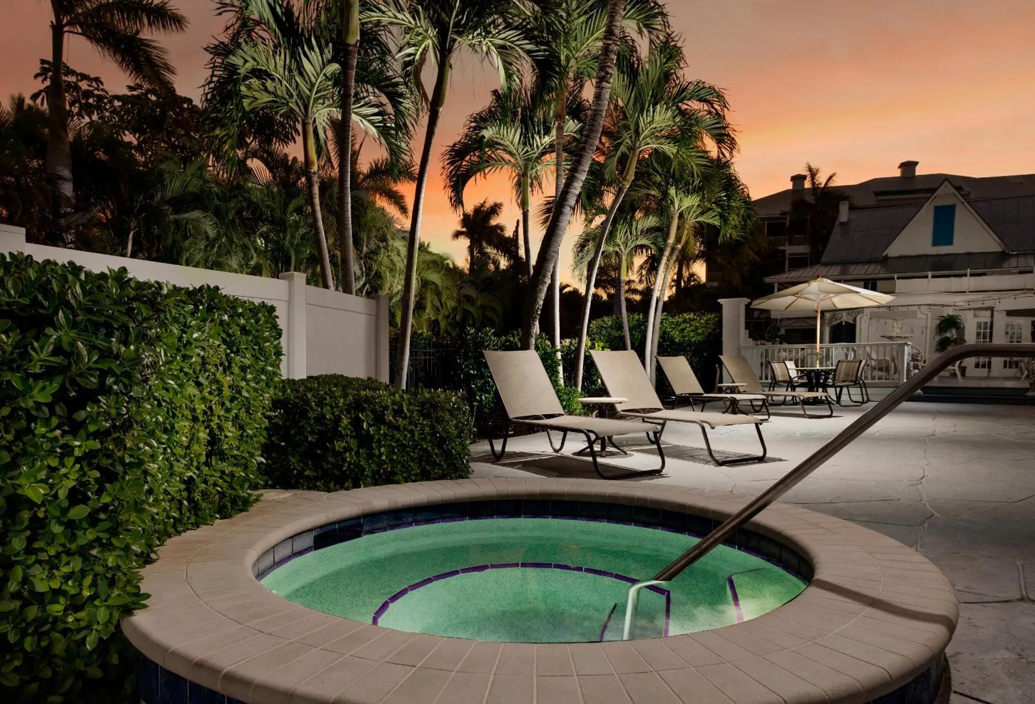 Un jacuzzi et des transats invitent à la détente dans un jardin tropical au crépuscule.