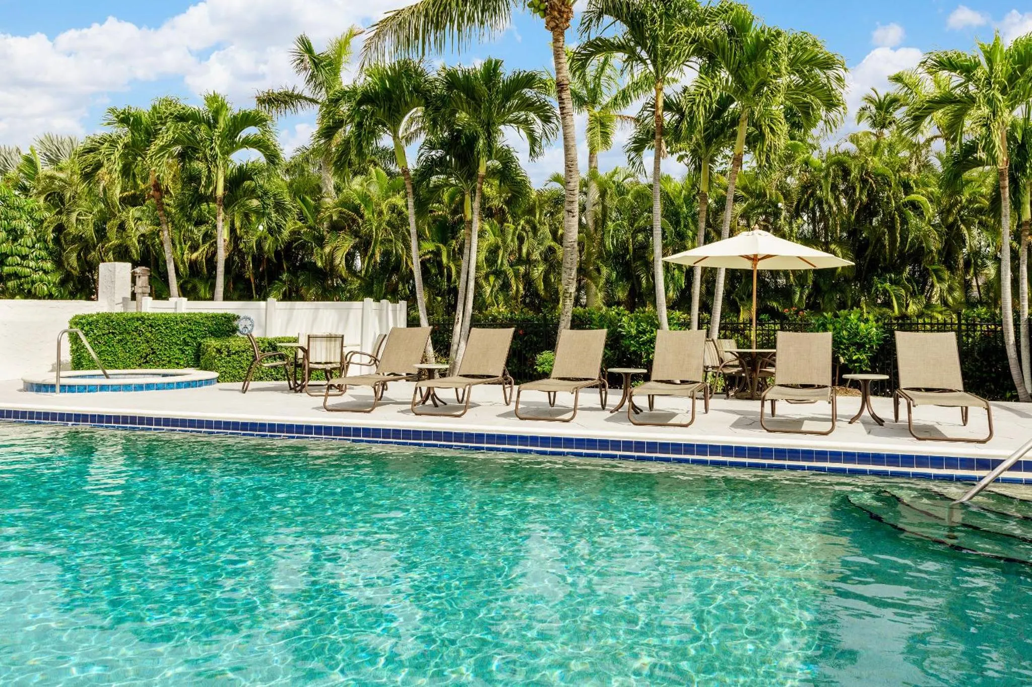 Transats alignés au bord d'une piscine turquoise entourée de végétation tropicale.