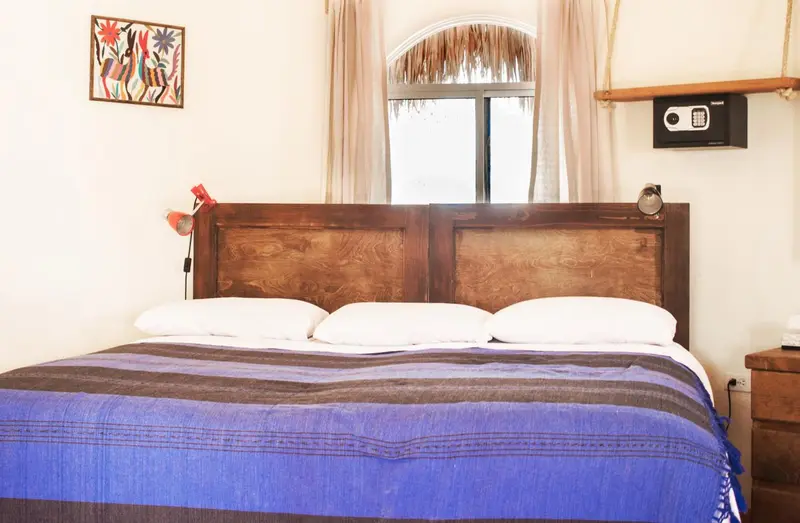 Une chambre lumineuse avec un grand lit recouvert d'une couverture colorée.