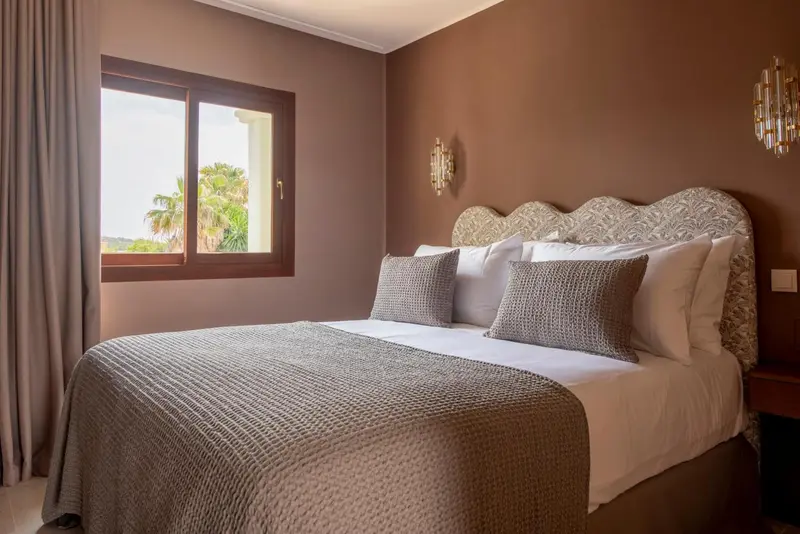Une chambre avec un grand lit et une fenêtre donnant sur un paysage.
