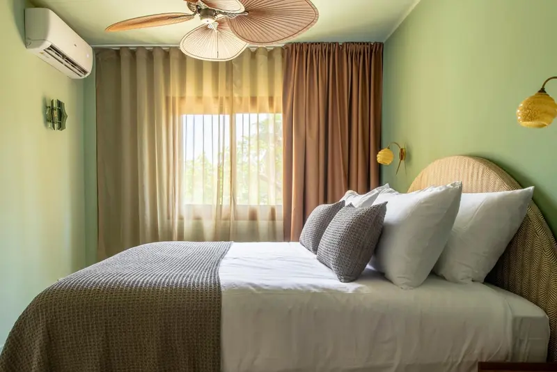 Une chambre lumineuse avec un lit recouvert d'une couverture et de coussins.