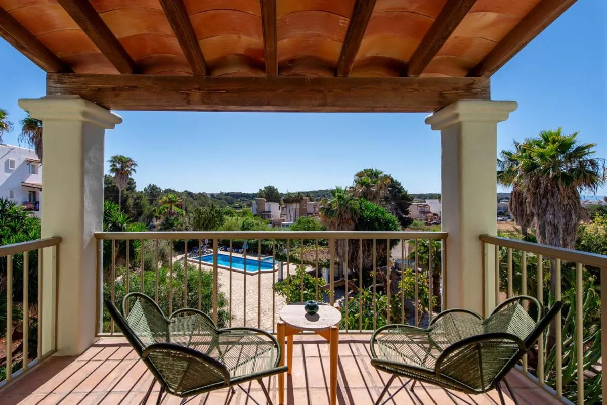 Terrasse ombragée avec mobilier de jardin donnant sur une piscine et un paysage verdoyant.