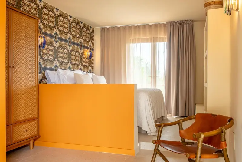 Une chambre lumineuse avec un lit et un fauteuil.