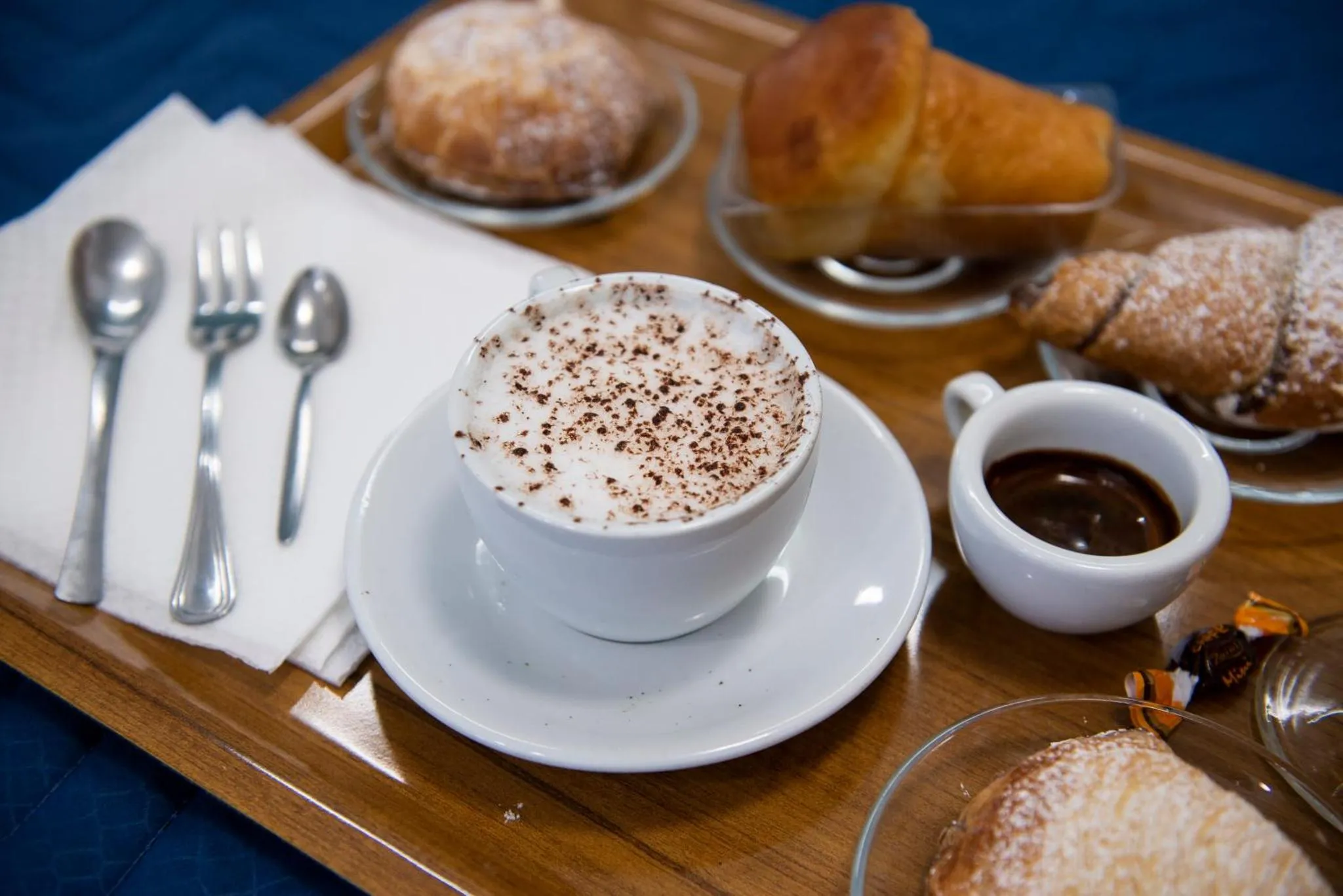 Une sélection de viennoiseries et une boisson chaude sont présentées sur un plateau en bois.