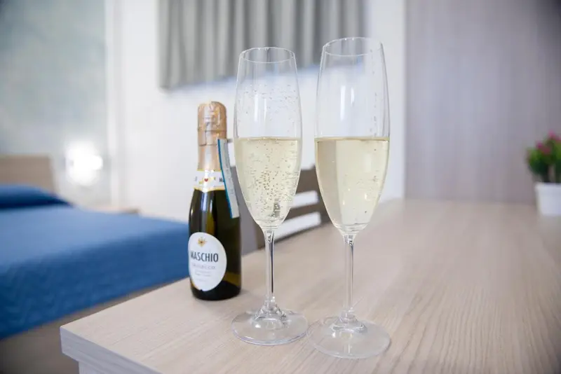 Deux coupes de champagne et une bouteille sur une table claire.