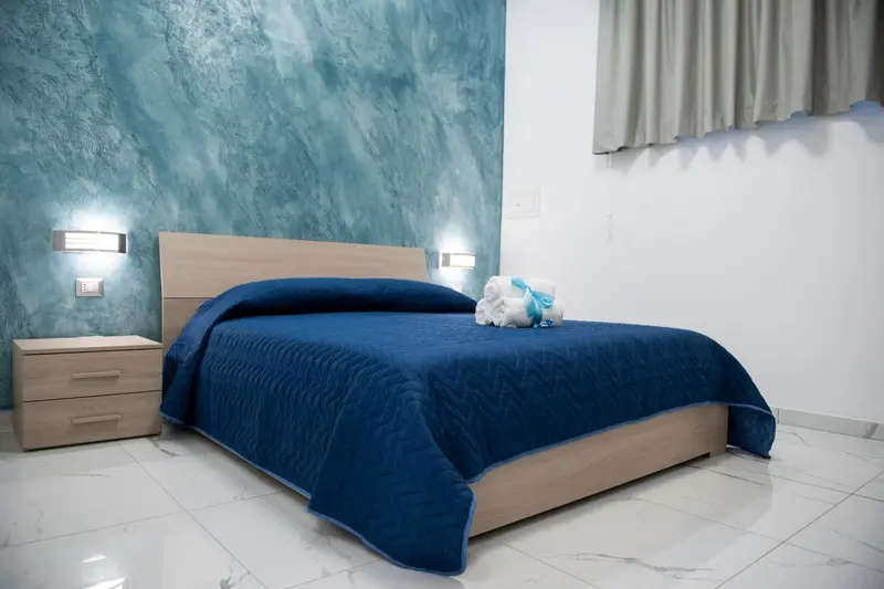 Une chambre avec un grand lit recouvert d'une couette bleue.