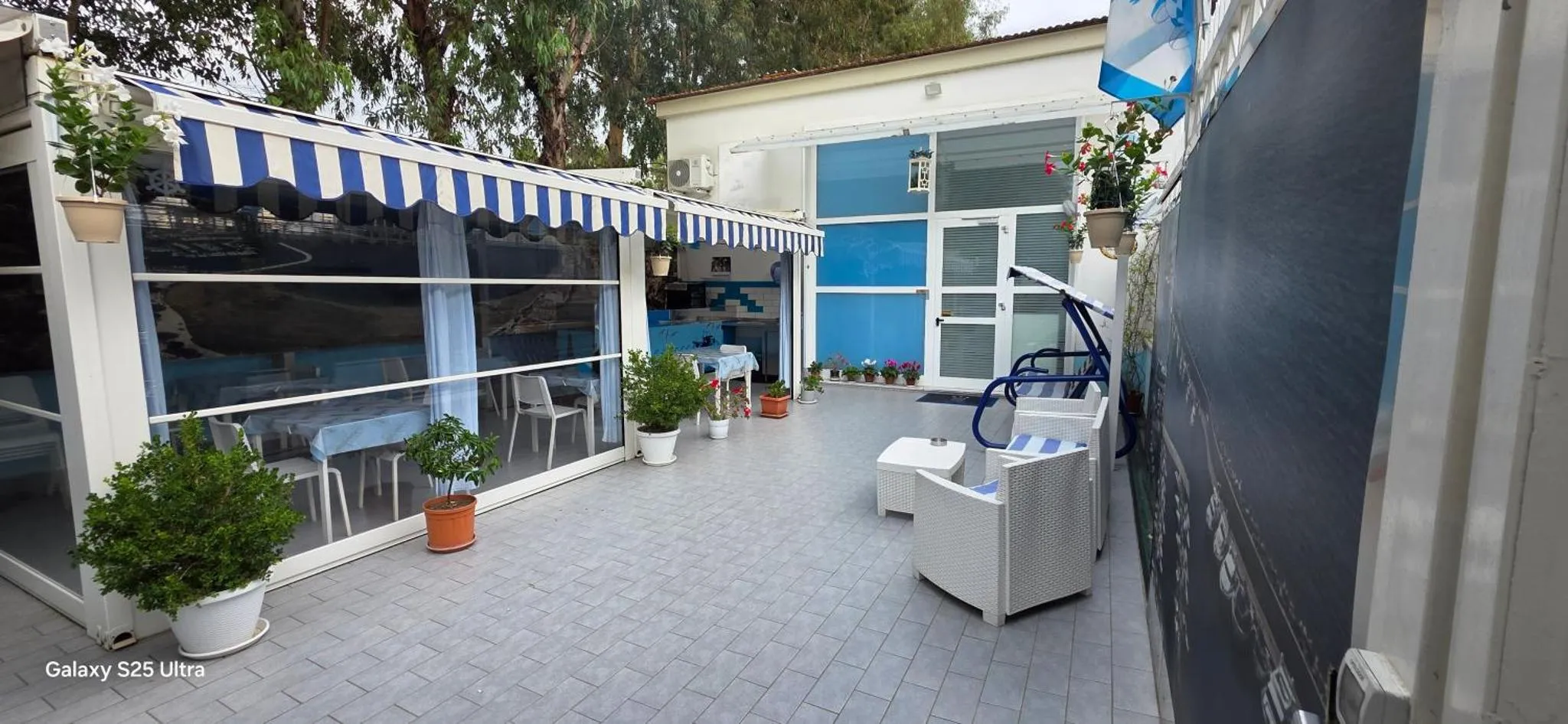 Terrasse ombragée avec mobilier d'extérieur et plantes en pots.