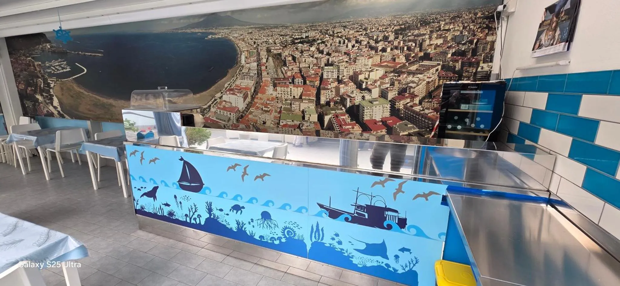 Une salle lumineuse avec un comptoir décoré de motifs marins et des tables à manger.