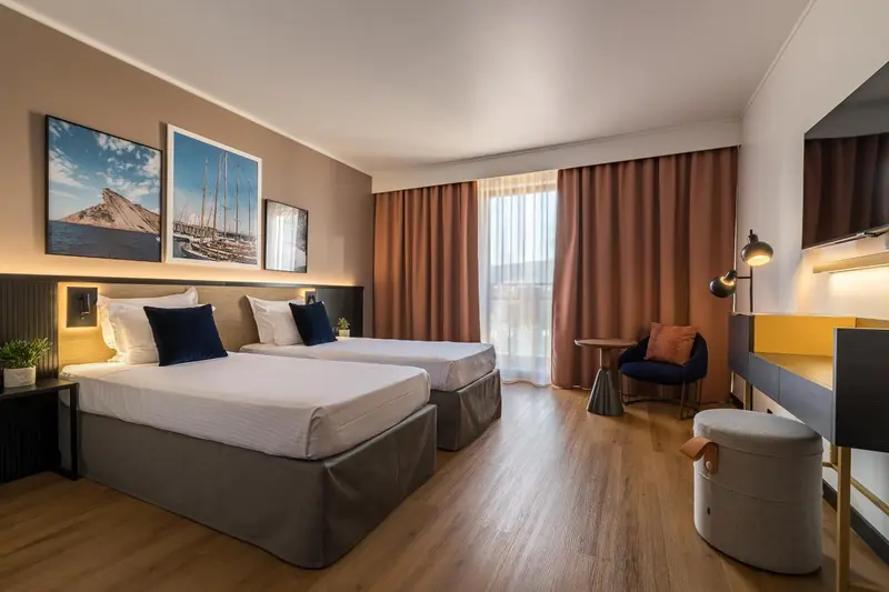 Une chambre lumineuse avec deux lits simples et un coin salon.